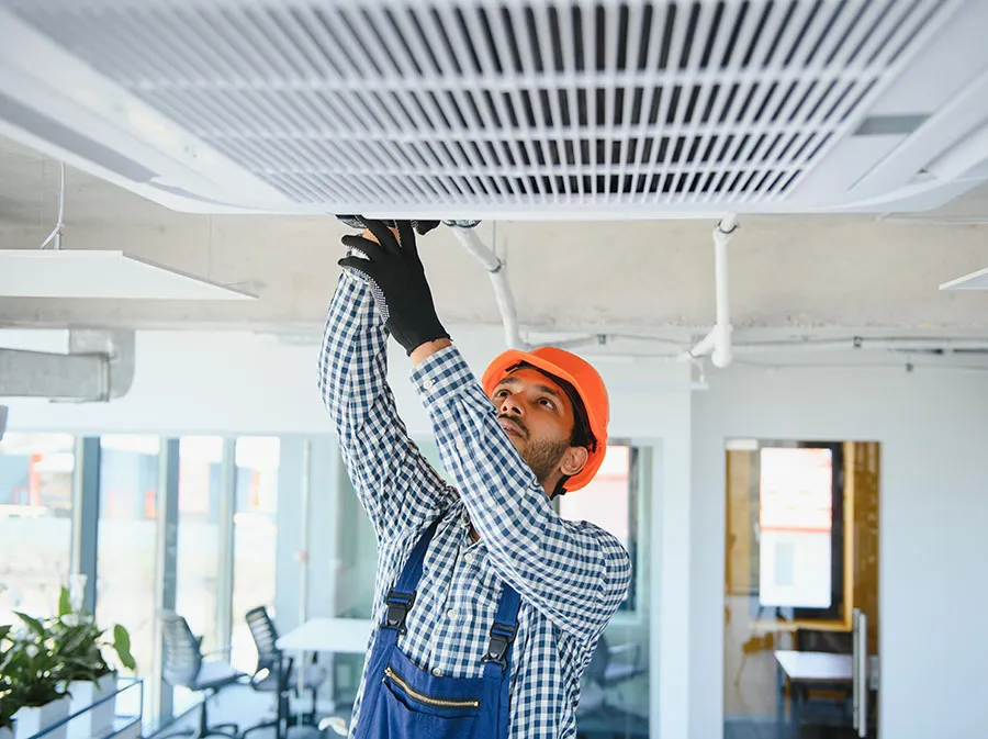 Professional technician maintaining modern air purification equipment in commercial setting